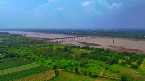 The bridge over a river near the large green farmland, connecting roads and fields landscape