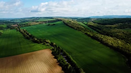 Aerial landscape slideling shot of cloudy bright and shady view of agricultural areas hills and litt