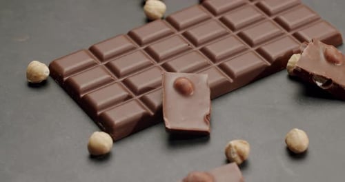 CloseUp of Chocolate Bar With Hazelnuts on Dark Background