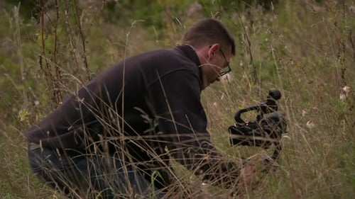 Man with Camera Gimbal in Grassy Field