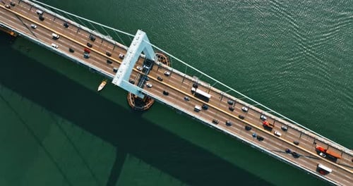Flight above the beautiful bridge with six-lane road on. Yacht sailing under the bridge. Top view.