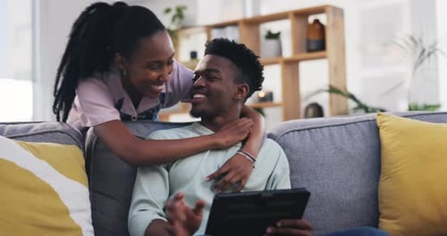 Affectionate Couple Embracing on Couch Using Tablet