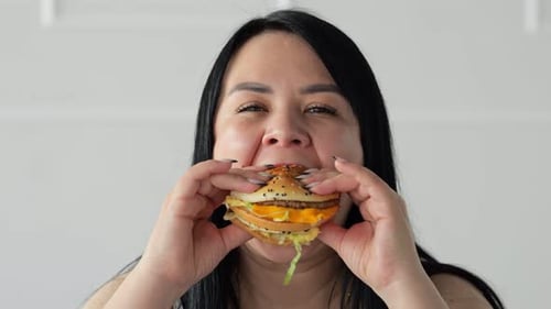 Darkhaired Woman Enjoys Eating Burger From Fast Food Cafe