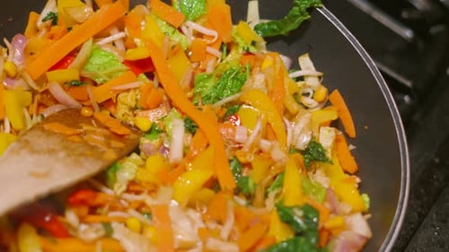 Top Rotating View of Colorful Oriental Stir Fry Vegetables in Hot Wok Pan including Carrots, Beanspr