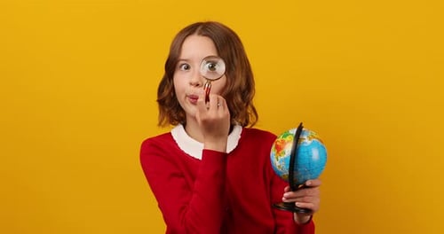 Stylish Smiling School Teenage Girl Holding Magnifying Glass in Her Hand and Look on Globe