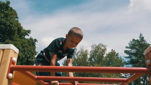 Child Plays in the Playground on the Uneven Bars Against the Sky in Slow Motion