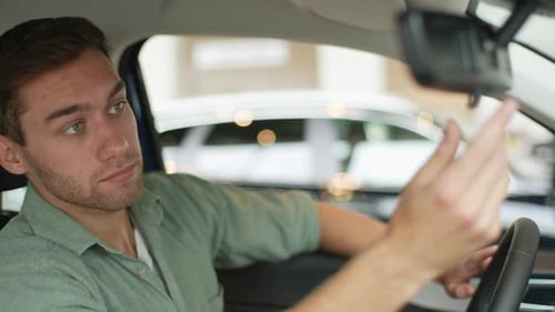 Man Adjusting Rearview Mirror in New Car
