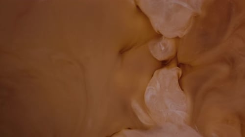 Milk pouring into coffee slow motion.