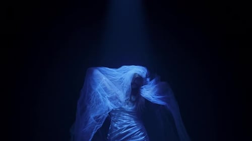 Woman in wedding dress poses in dark studio