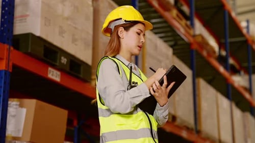 Warehouse Manager in Helmet Using Tablet for Checking Goods