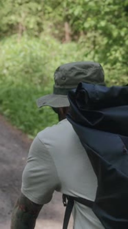 Radfahrer fährt auf Waldstraße, Kamera folgt von hinten links
