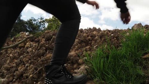 Woman climbing up dirt and rocks. Static