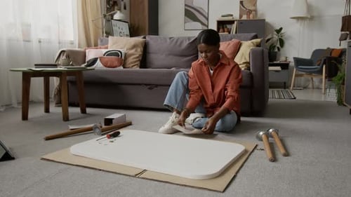 Instructions d'assemblage pour femme noire retroussant la manche de sa chemise et sa table de lecture