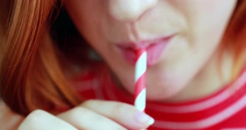 Young woman mouth drinking from straw