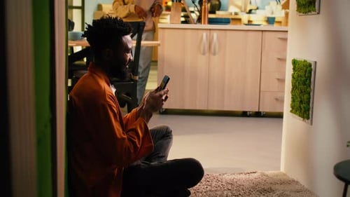Afroamerikanischer Mann entspannt sich zu Hause und checkt Textnachrichten