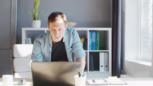 Un jeune entrepreneur de sexe masculin travaille au bureau à domicile sur le lieu de travail informatique d'un travailleur indépendant ou d'un étudiant