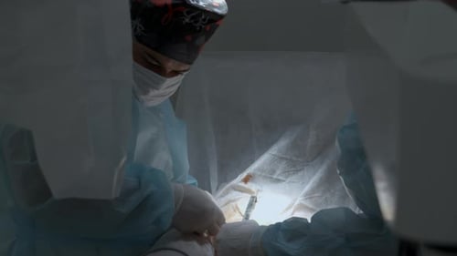Männlicher Chirurg mit Maske und Kappe bei der Durchführung einer Blepharoplastik mit medizinischem Instrument