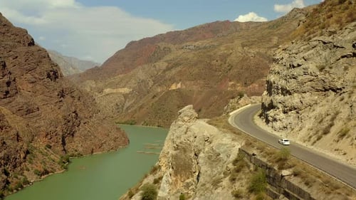 tranquil expanses of the Naryn River along picturesque rocky mountains and winding roads with a car