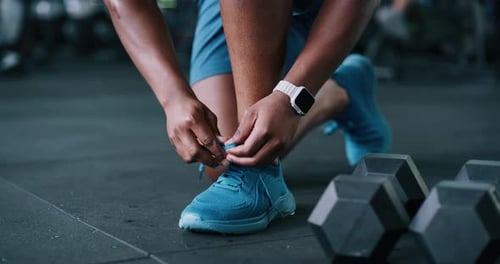 Person, hands and tying with shoes in gym for fitness, workout preparation or start exercise