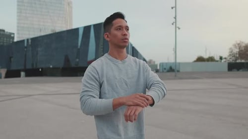 Man Warming Up for Jog in City