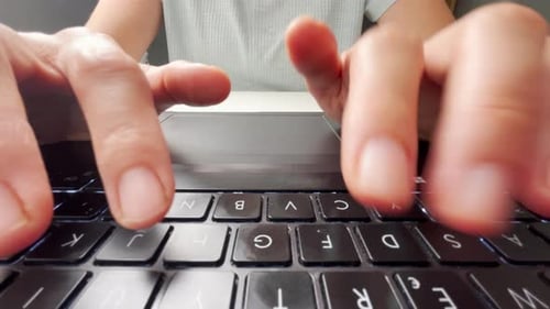 Fingers Typing on Laptop Keyboard in Office Setting