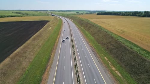 Aerial View of a Cars Driving Through Highway Road Among Agriculture Fields and Green Countryside