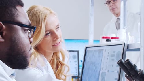 Scientists examining microscope images in a research lab