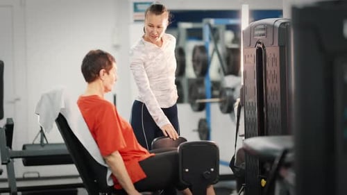 Woman works out with trainer at the gym.