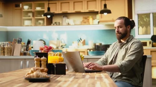 Man Working on Laptop at Kitchen Table