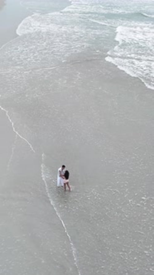 Romantic couple embrace on beach shoreline aerial view
