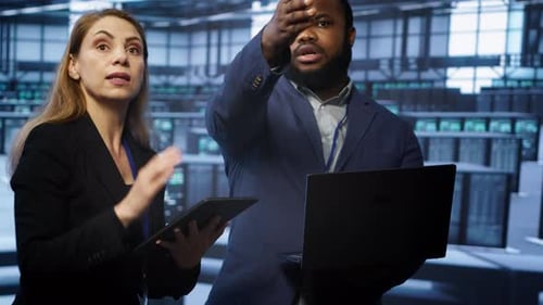Coworkers in Server Room Optimizing Data Center Tech with Laptop and Tablet