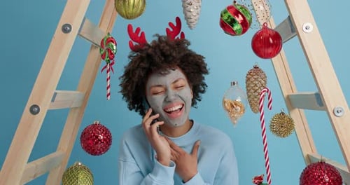 Woman with face mask talking on phone with reindeer antlers