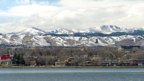 Time lapse of the Sloan Lake shoreline in Denver, Colorado with snow covered Rocky Mountains in the