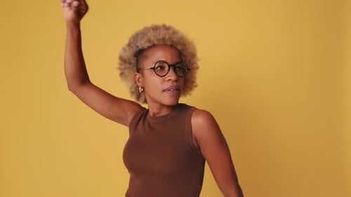 Woman Dancing and Smiling on Yellow Background
