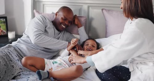 Joyful Family Laughing and Playing Together on Bed
