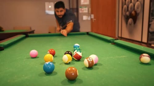 Casual player hitting starting position shot billiard balls triangle white cue ball seen in a distan