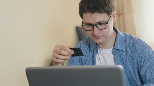 Young Adult Uses Laptop With Credit Card Indoors