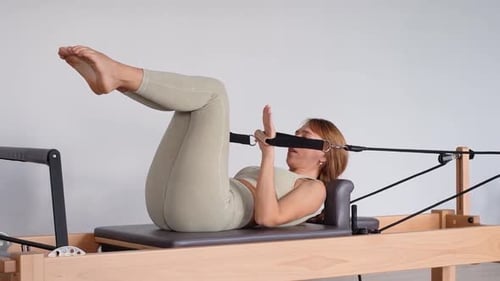 Woman Doing Pilates on Reformer Machine