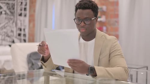 Young Adult Reviews Documents at Home Desk