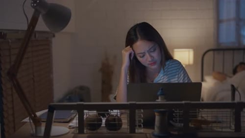 Woman Working at Laptop in Dimly Lit Room