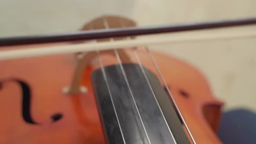 Close up of hand playing cello with cello bow.