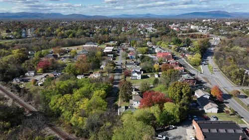 Aerial wide shot of charming city in USA with colored trees in autumn. Single family houses along