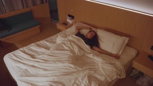 Woman Relaxes in Cozy Hotel Female Traveler Enjoys Restful Morning in Charming Hotel Room Solo