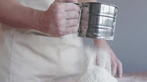 Person Sifting Flour for Baking Preparation