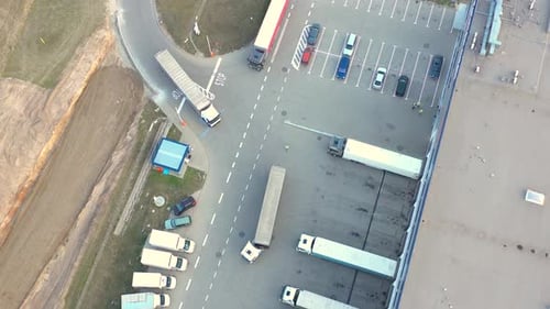 Aerial view of a semi trucks with cargo trailers standing on warehouses ramps for loading/unloading