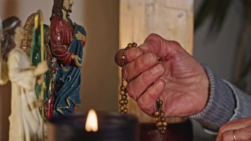 Hands Of Lady Praying Rosary And Statues Of Jesus Mary And Angel