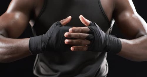 African American boxer wraps his hands for boxing on a black background