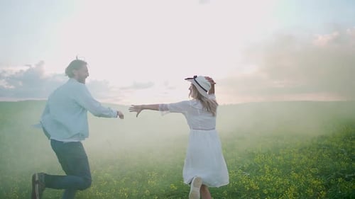 Countryside Cheerful Couple in Nature Man and a Woman are Running Through a Field of Rapeseed