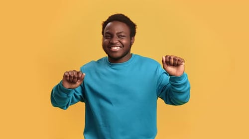 Overjoyed Happy Young African American Casual Man Dancing Posing Isolated on Orange Studio