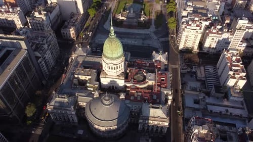 Aerial tracking shot of Palace of the Argentine National Congress and traffic on road during sunset